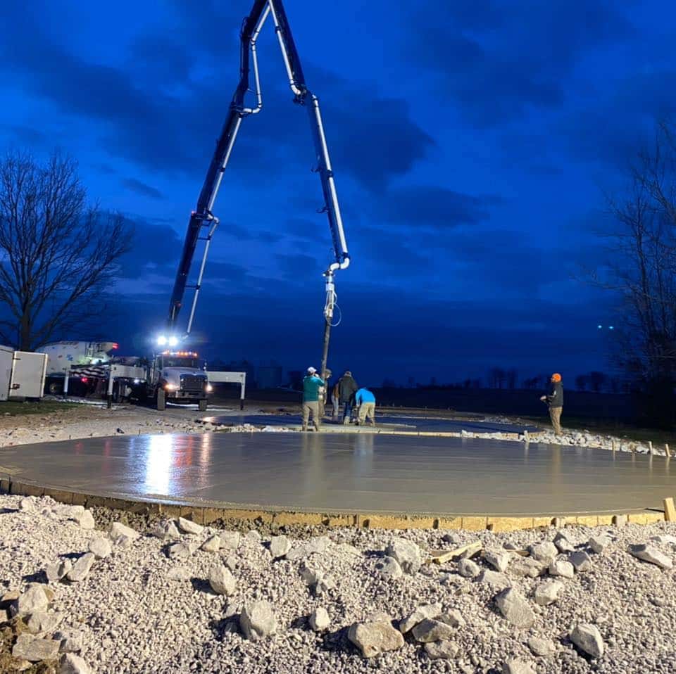 Four Rivers crew finishing a large concrete slab at dusk with a concrete pump truck near Paducah, KY